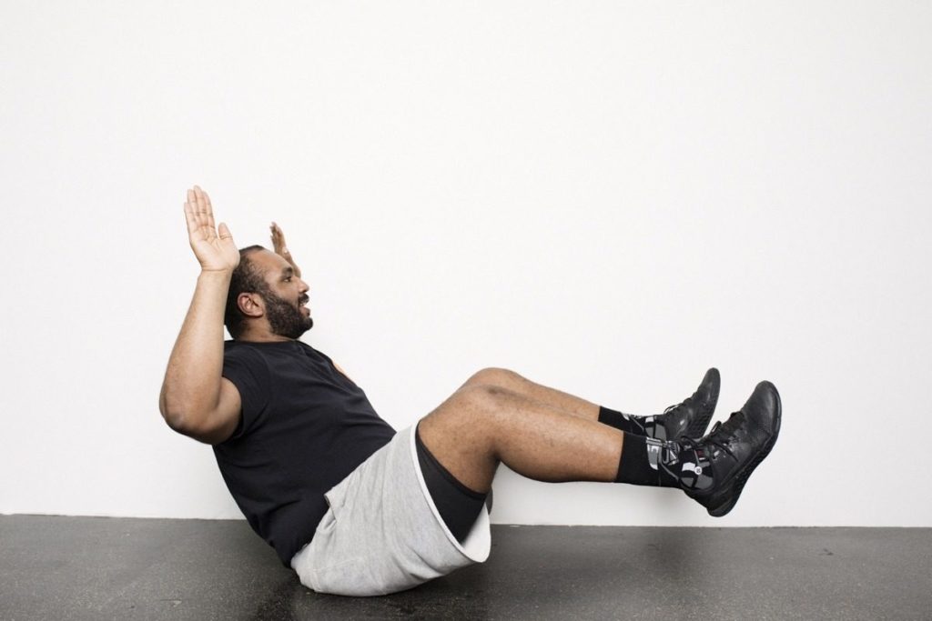 Personal Trainer zeigt Fitnessübung für Bauch